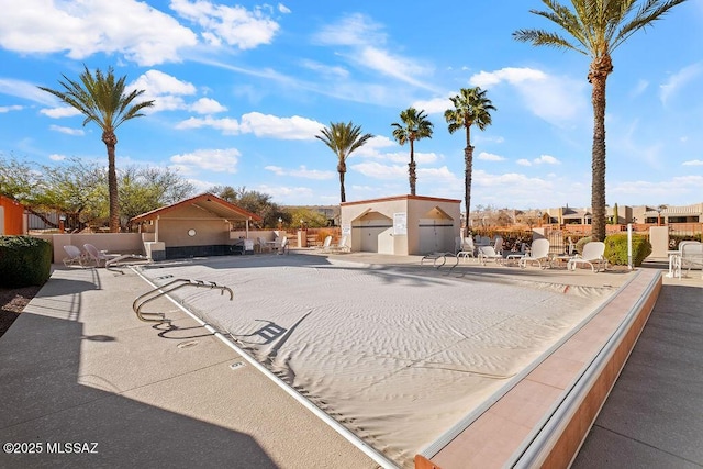 view of front facade with a community pool, fence, and a patio