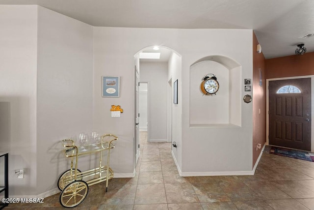 tiled entryway featuring arched walkways, visible vents, and baseboards