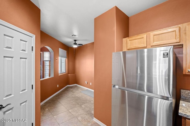 kitchen featuring visible vents, a ceiling fan, light brown cabinets, light tile patterned flooring, and freestanding refrigerator
