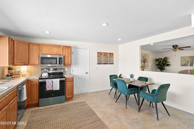 kitchen featuring recessed lighting, stainless steel appliances, a ceiling fan, baseboards, and tile counters