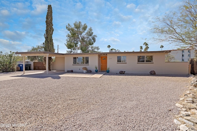 rear view of house with driveway, fence, and an attached carport