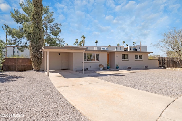 single story home with concrete driveway, a carport, and fence