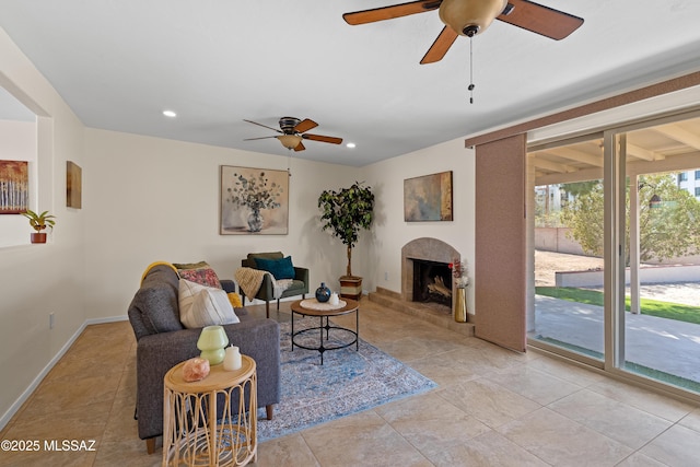 living area featuring light tile patterned flooring, baseboards, a fireplace with raised hearth, and recessed lighting