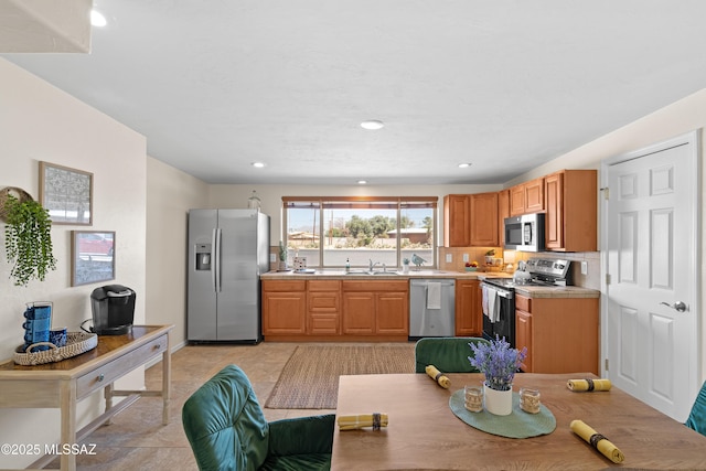 kitchen with baseboards, stainless steel appliances, light countertops, a sink, and recessed lighting