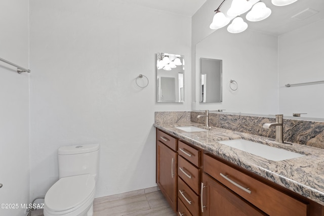 bathroom featuring double vanity, a sink, and toilet