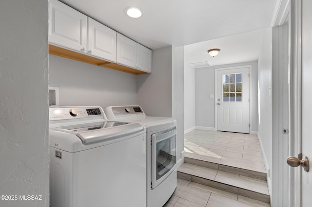 laundry area featuring baseboards, cabinet space, and washer and dryer