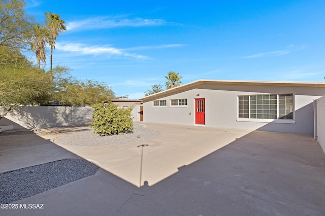 exterior space with fence, a patio, and stucco siding