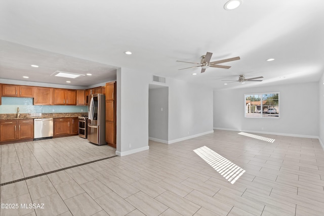 kitchen featuring visible vents, open floor plan, appliances with stainless steel finishes, backsplash, and brown cabinetry