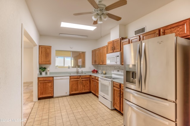 kitchen featuring white appliances, visible vents, brown cabinets, and a sink