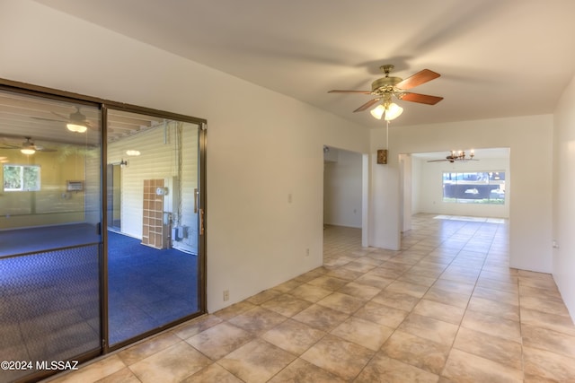 unfurnished room featuring ceiling fan with notable chandelier and light tile patterned floors