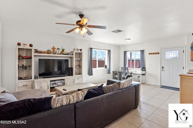 living room featuring light tile patterned floors, ceiling fan, visible vents, and baseboards