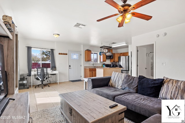 living room featuring ceiling fan, light tile patterned flooring, visible vents, and baseboards