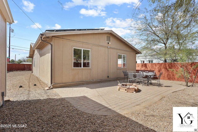 back of house featuring outdoor dining space, a patio area, a fenced backyard, and roof mounted solar panels