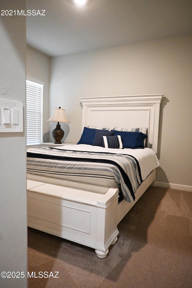 bedroom with dark colored carpet and baseboards