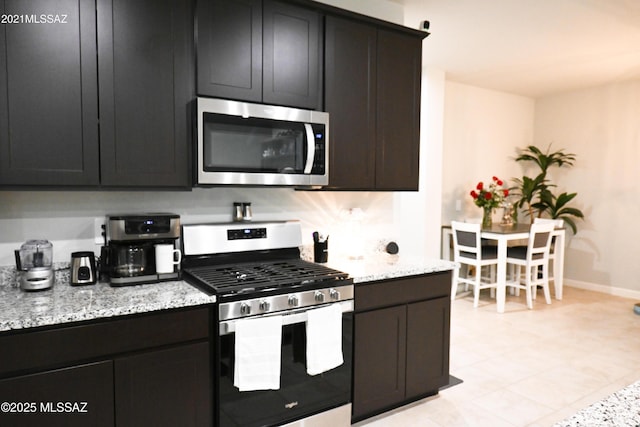 kitchen featuring appliances with stainless steel finishes, light stone counters, and baseboards