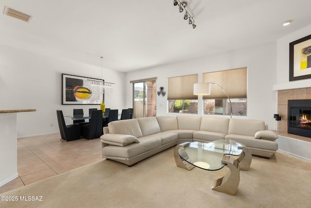 carpeted living room featuring visible vents, baseboards, tile patterned floors, a tiled fireplace, and track lighting