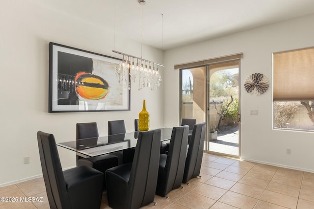 dining area with a notable chandelier, light tile patterned flooring, and baseboards