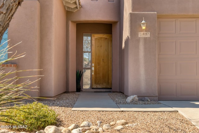 view of exterior entry featuring a garage and stucco siding