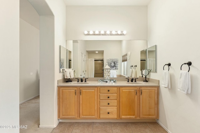 bathroom with double vanity, tile patterned flooring, a sink, and a shower with shower door