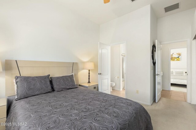 bedroom with light carpet, light tile patterned floors, baseboards, visible vents, and connected bathroom