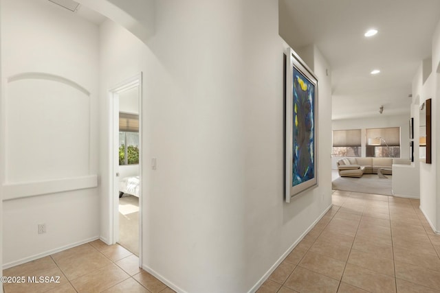 corridor featuring light tile patterned floors, baseboards, and recessed lighting