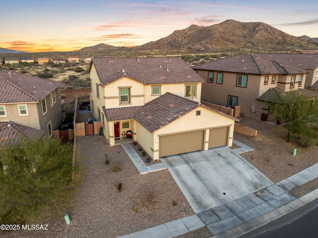 view of front facade with driveway, a tile roof, fence, a mountain view, and stucco siding