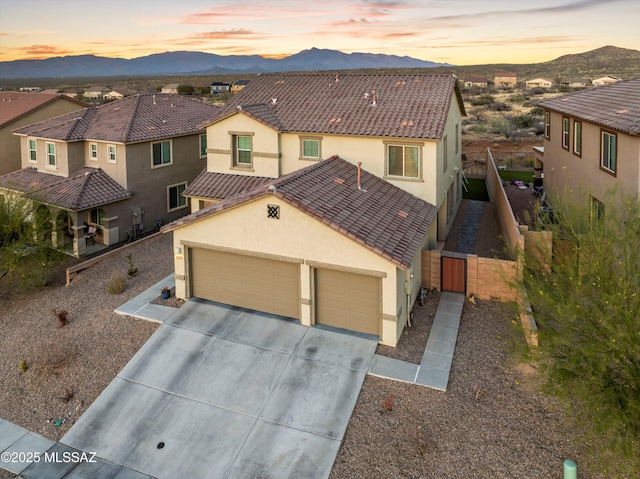 view of front of property with concrete driveway, a tile roof, an attached garage, fence, and stucco siding