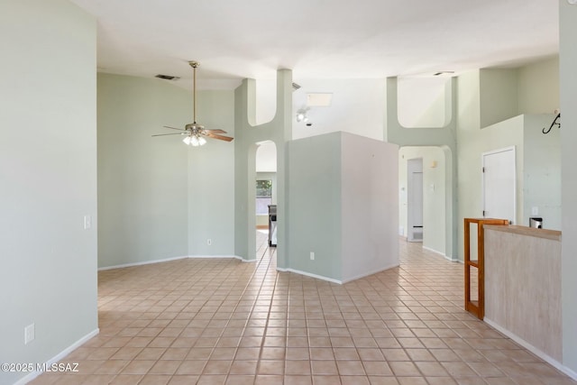 unfurnished room featuring light tile patterned floors, ceiling fan, high vaulted ceiling, and baseboards