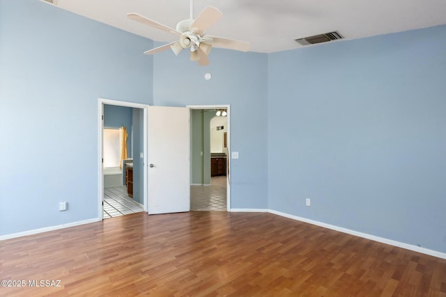 unfurnished bedroom with visible vents, ensuite bath, baseboards, and wood finished floors