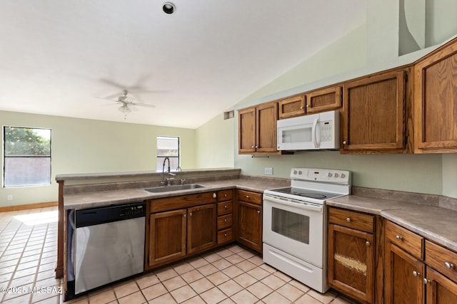 kitchen with brown cabinetry, plenty of natural light, white appliances, and a sink