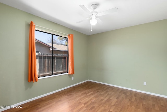 empty room with ceiling fan, baseboards, and wood finished floors