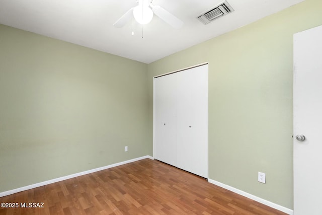 unfurnished bedroom featuring a closet, wood finished floors, visible vents, and baseboards