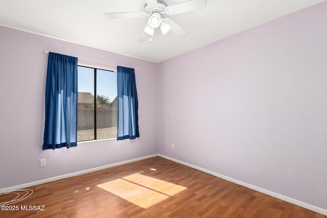 spare room with ceiling fan, wood finished floors, and baseboards