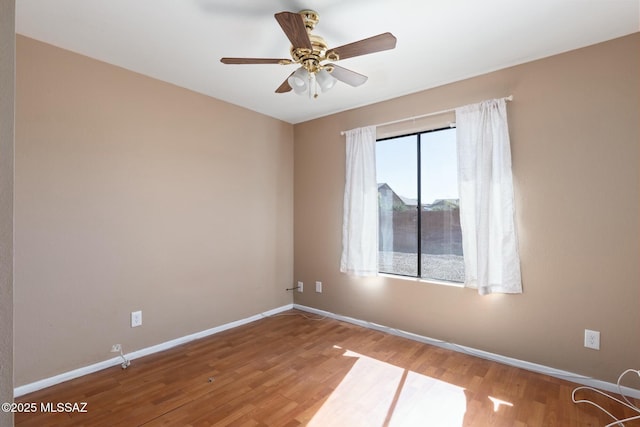 empty room featuring ceiling fan, baseboards, and wood finished floors