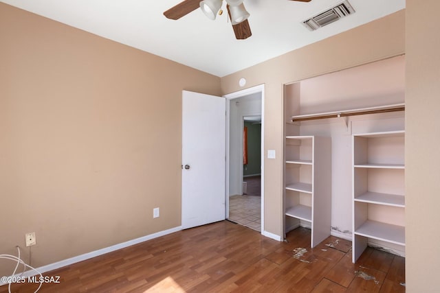 unfurnished bedroom with a ceiling fan, baseboards, visible vents, and wood finished floors