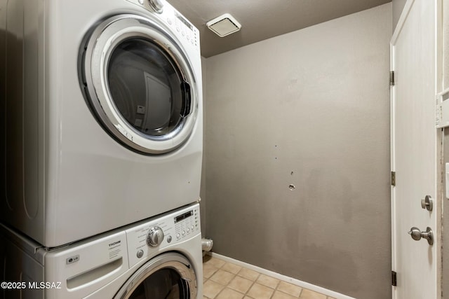 laundry room featuring stacked washer and dryer, laundry area, and light tile patterned flooring