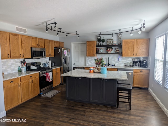 kitchen with stainless steel appliances, a sink, a center island, dark wood-style floors, and open shelves