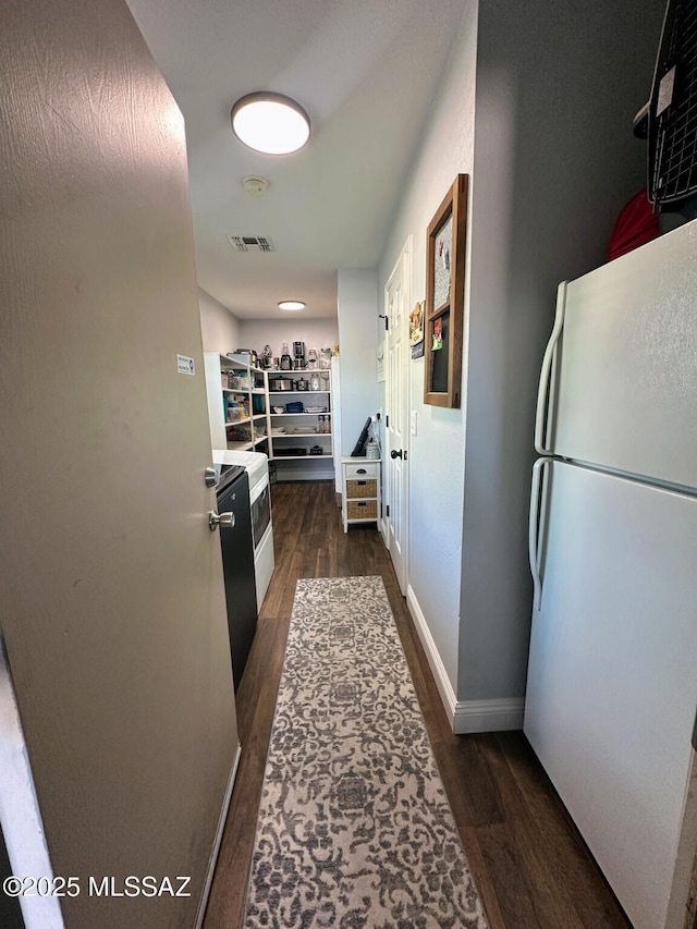 corridor with dark wood-style flooring, visible vents, and baseboards