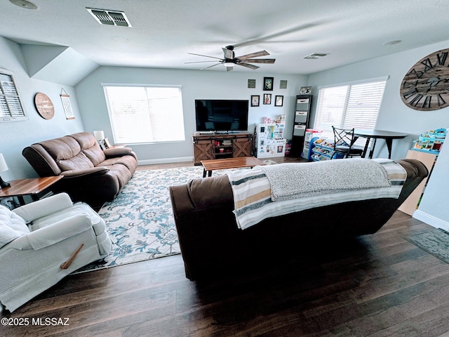 living area featuring dark wood-type flooring, visible vents, baseboards, and a ceiling fan