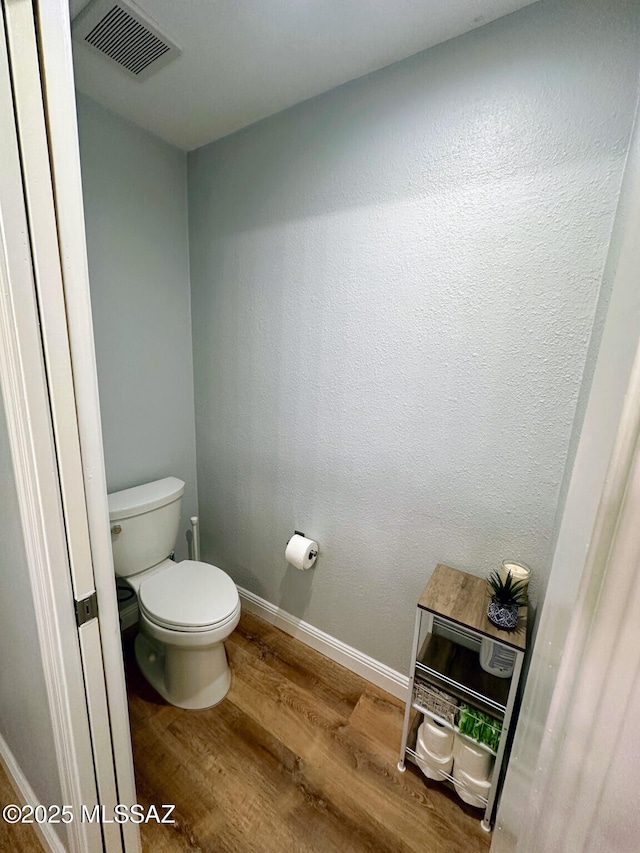 bathroom featuring baseboards, visible vents, toilet, and wood finished floors