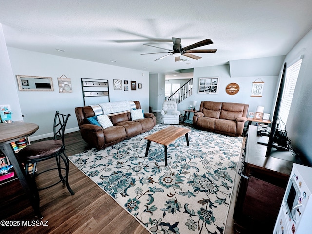 living area with a textured ceiling, dark wood-type flooring, stairway, and baseboards