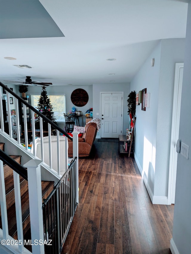 corridor featuring stairs, dark wood-style flooring, visible vents, and baseboards