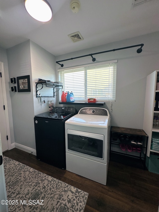 kitchen featuring baseboards, visible vents, dark wood-type flooring, and washing machine and clothes dryer