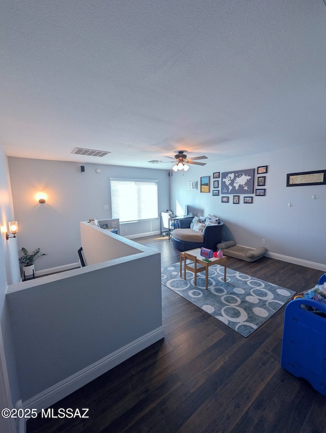 living area with visible vents, ceiling fan, a textured ceiling, wood finished floors, and baseboards