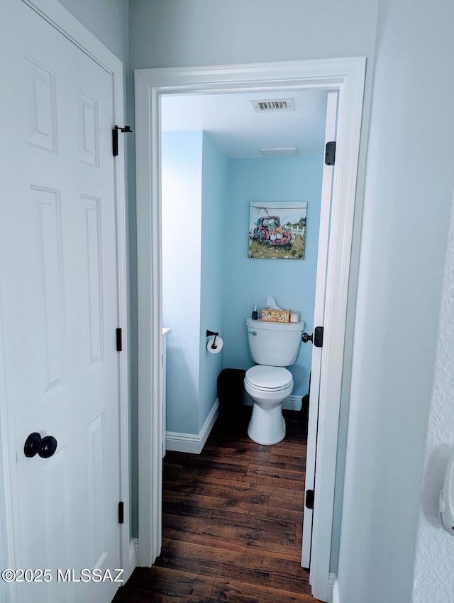 bathroom with baseboards, visible vents, toilet, and wood finished floors