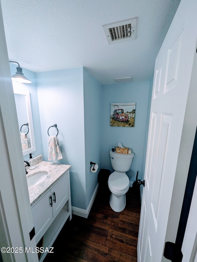 bathroom featuring visible vents, toilet, wood finished floors, a textured ceiling, and vanity