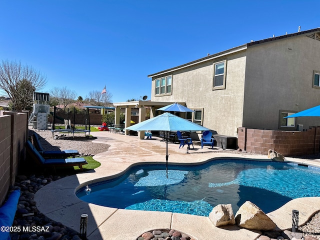 view of pool featuring a trampoline, a patio area, fence, and a fenced in pool