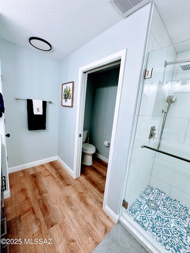 bathroom with toilet, wood finished floors, visible vents, and a shower stall