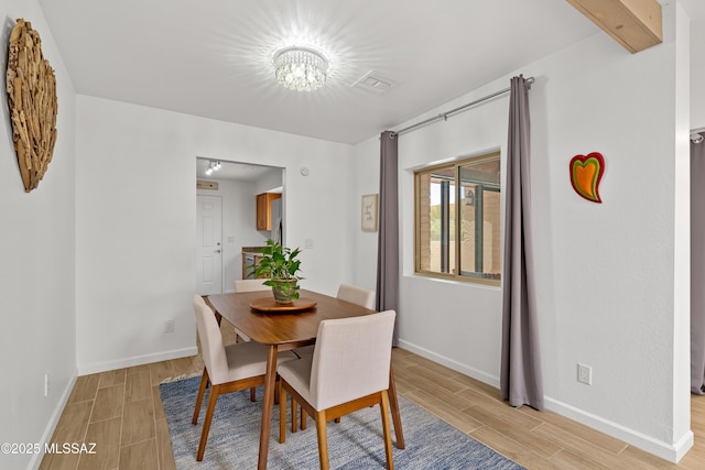 dining area featuring visible vents, baseboards, and wood tiled floor