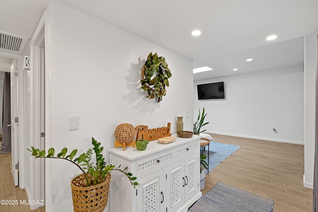 hall featuring light wood-style flooring, recessed lighting, visible vents, and baseboards